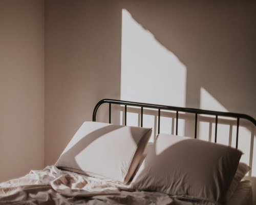 A clean glass of water next to a neatly made bed indicating healthy rest routines