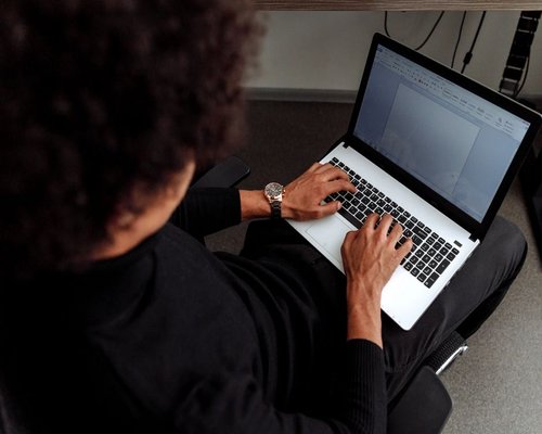 A professional typing on a laptop in a well-lit co-working space in Bandung